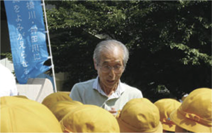 Mr. Isamu Hayashi (Chairman of the Revive Clean Water in Nihonbashi River and Kanda River Group) speaking to local elementary school children who participated in EM Bokashi fermented Mudball project